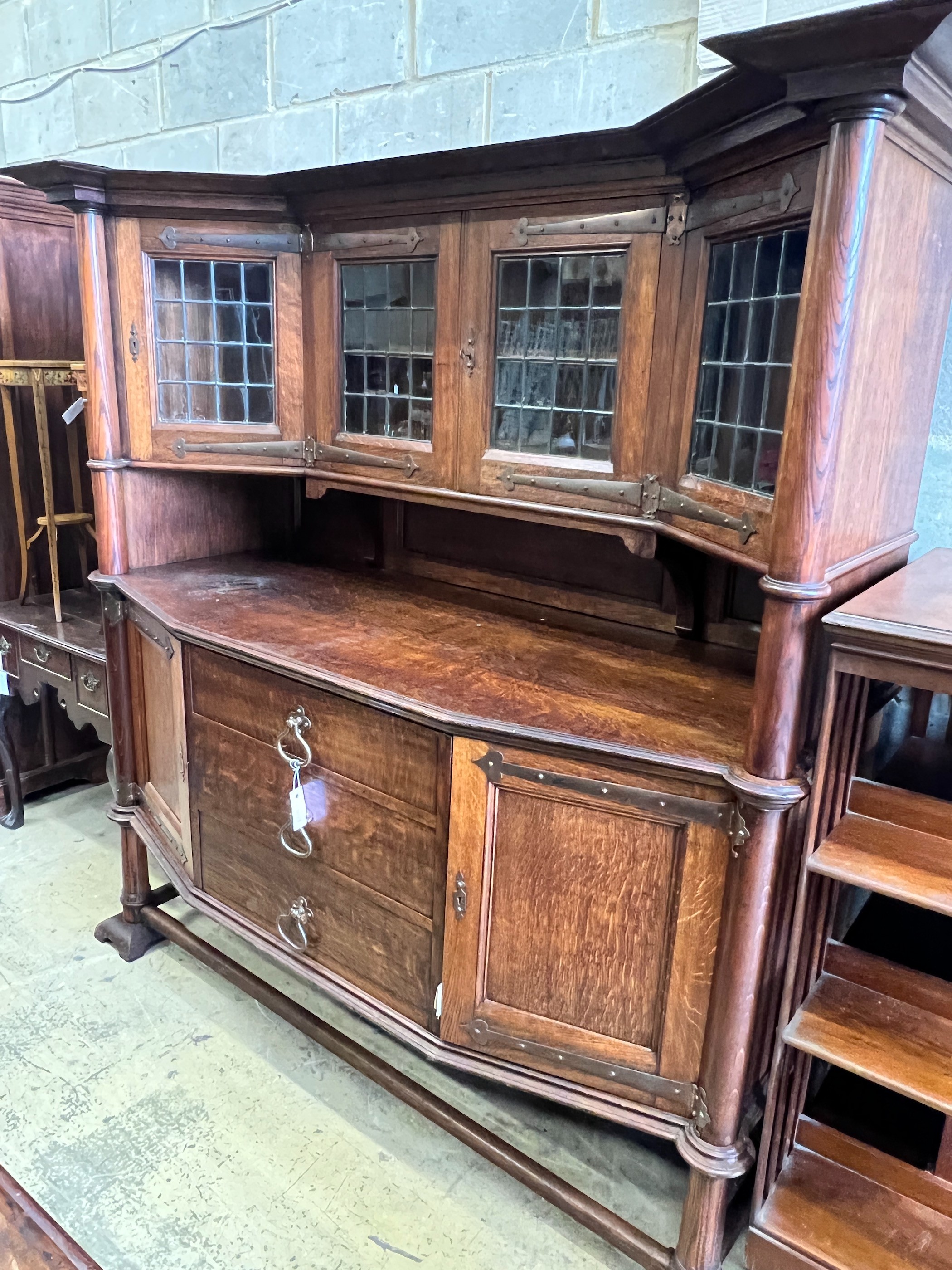 An early 20th century Arts & Crafts copper mounted oak sideboard in the manner of Shapland and Petter, stamped Warings, Oxford Street, London, length 168cm, width 64cm, height 180cm